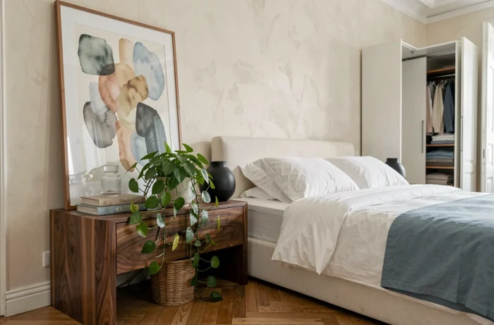 Coin chambre parisienne luxueuse avec table de nuit en noyer, literie en percale et décoration sculpturale
